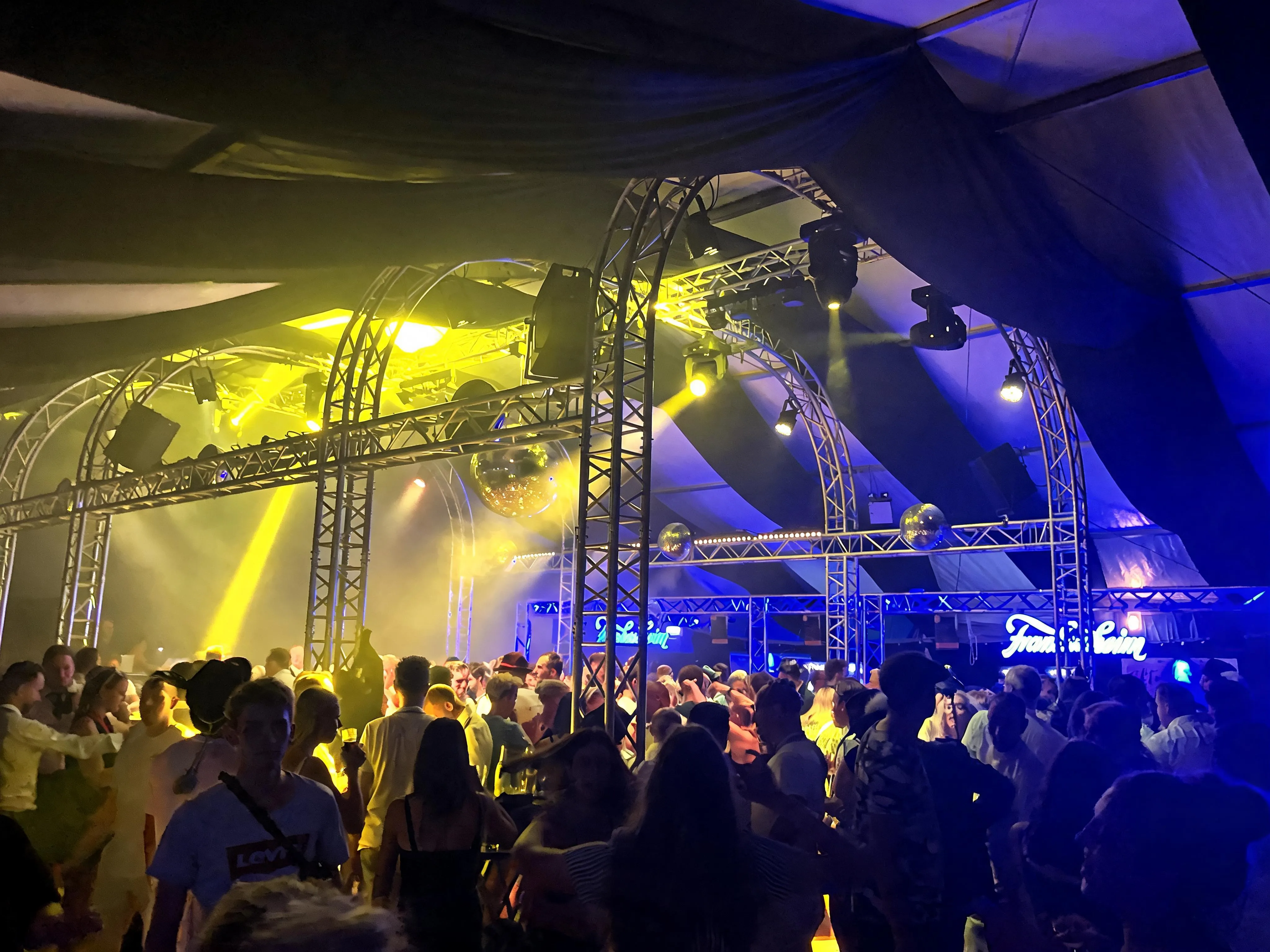 Volle Tanzfläche im Partyzelt: Truss-Bögen, Discokugeln und Lichtsäulen über der Menge