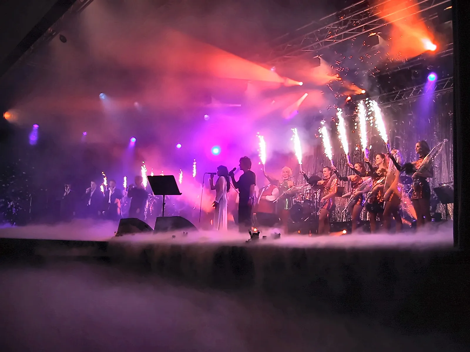 Finale einer Gala: Ensemble mit Funkenfontänen auf der Bühne, rotes und blaues Showlicht