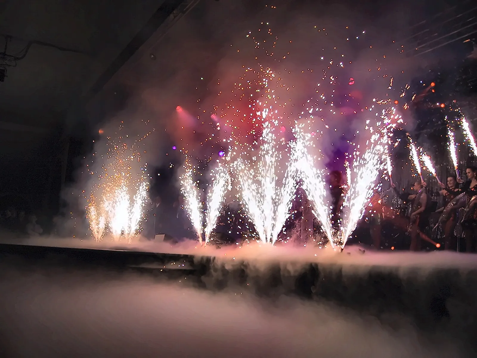 Gestochen scharfe Pyro-Fontänen auf der Bühne, rechts Tänzerinnen im Scheinwerferlicht